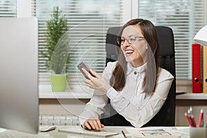 Beautiful business woman in suit and glasses working at computer with documents in light office