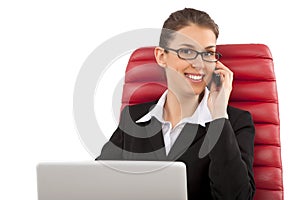 Beautiful business woman talking on mobile phone sitting on a red chair in office