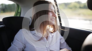 Beautiful business woman traveling in a taxi to an important meeting and corresponding with colleagues using a