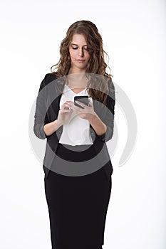 A beautiful business woman in a white blouse and black skirt is typing a message on her mobile phone