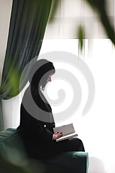 Beautiful business woman writing something in the note pad while sitting on the sofa at office, charming brunette female