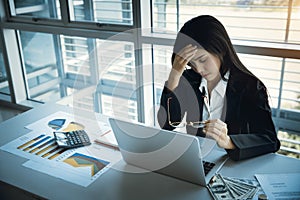 Beautiful businesswoman holding glasses got stress and headache with computer on table