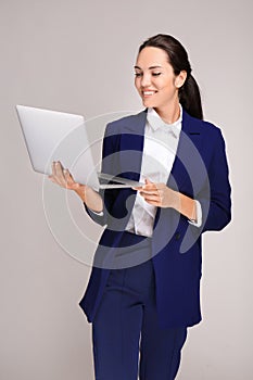 Beautiful businesswoman with laptop on grey background