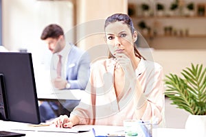 Beautiful businesswoman looking nervous while sitting at office desk and working on computer