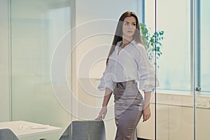 Beautiful businesswoman looks around in a glass office