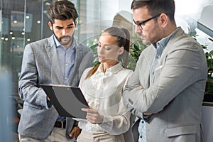 Beautiful businesswoman with male colleagues discussing about work in an office.