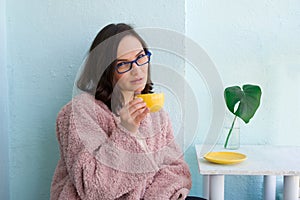 beautiful businesswoman in pink fur coat and glasses holding yellow coffee cup in cafe during lunch break