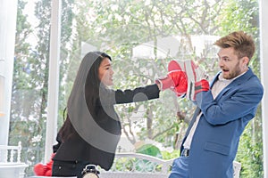 Beautiful businesswoman is punching a young businessman with boxing