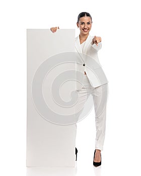 beautiful businesswoman showing empty board and pointing finger forward