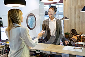 Beautiful businesswoman takes room key card and doing check-in at the hotel reception