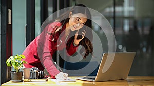 Beautiful businesswoman taking notes while having business talk on the phone