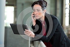 Beautiful businesswoman using digital tablet at office railing
