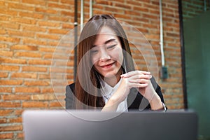 A beautiful businesswoman using earphone for video conference on laptop computer while working online