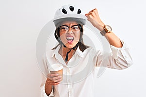 Beautiful businesswoman wearing bike helmet drinking coffee over isolated white background annoyed and frustrated shouting with