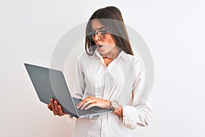 Beautiful businesswoman wearing glasses using laptop over isolated white background scared in shock with a surprise face, afraid