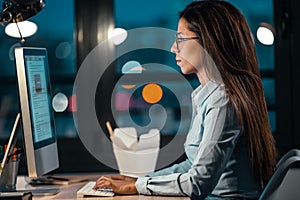 Beautiful businesswoman working with computer in the office at night