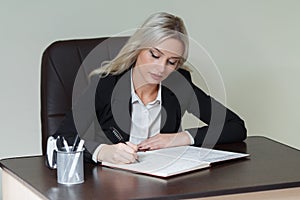 Beautiful businesswoman writing in a notebook in office.