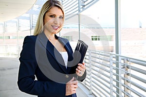 Beautiful businesswoman writing with portfolio