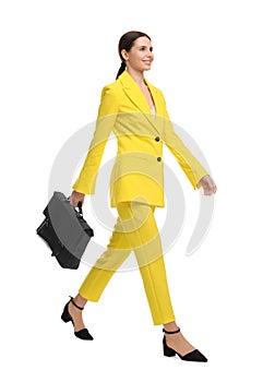 Beautiful businesswoman in yellow suit with briefcase walking on white background