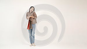 A beautiful, busy Asian woman is talking on the phone while carrying her shopping bags