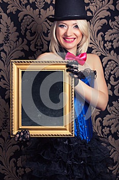Beautiful cabaret woman posing with golden frame against retro w