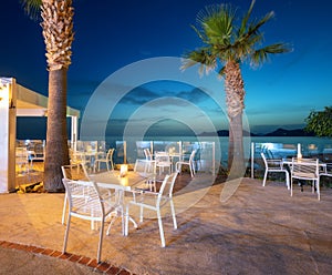 Beautiful cafe on sea coast at night in summer. Chairs and tables