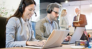 Beautiful call center smiling operator agent with phone headset working in office