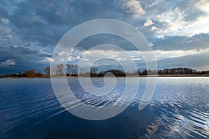 Beautiful calm blue lake, afternoon clouds on the sky