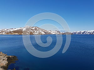 Beautiful calm blue ocean with mighty snowy island mountain range in the background on the Mageroy island, Finnmark, Norway