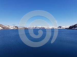 Beautiful calm blue ocean with mighty snowy island mountain range in the background on the Mageroy island, Finnmark, Norway