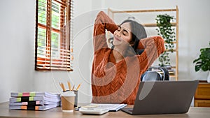 Beautiful calm Asian businesswoman relaxing at her desk during break