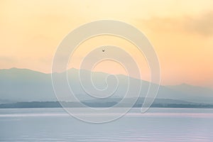 A beautiful, calm morning landscape of lake and mountains in the distance. Colorful summer scenery with mountain lake in dawn.