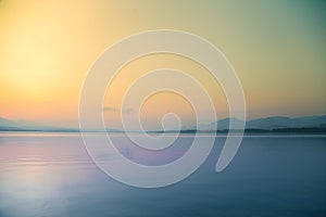 A beautiful, calm morning landscape of lake and mountains in the distance. Colorful summer scenery with mountain lake in dawn.