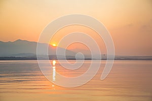 A beautiful, calm morning landscape of lake and mountains in the distance. Colorful summer scenery with mountain lake in dawn.