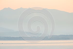 A beautiful, calm morning landscape of lake and mountains in the distance. Colorful summer scenery with mountain lake in dawn.