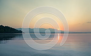 A beautiful, calm morning landscape of lake and mountains in the distance. Colorful summer scenery with mountain lake in dawn.