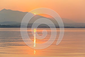 A beautiful, calm morning landscape of lake and mountains in the distance. Colorful summer scenery with mountain lake in dawn.