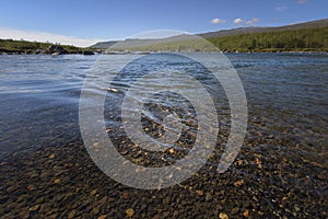 Beautiful calm ripples on the flowing water with amazing coloration river bottom stones