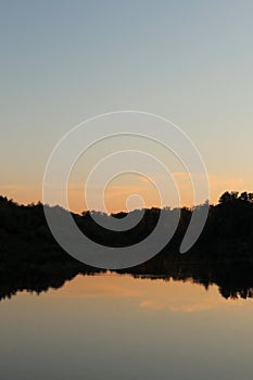 Beautiful calm sunrise dawn by the river with reflection on mirror water. Nice pastel colors nature landscape