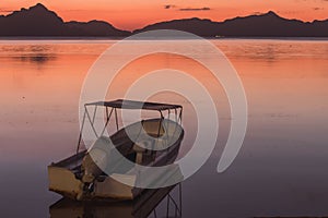 Beautiful calm sunset in Philippines, Palawan. Boat at sea with islands and mountains on horizon. Evening seascape panorama.