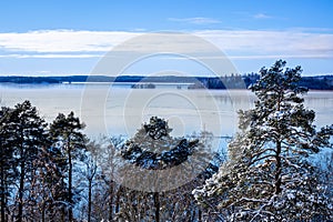 Beautiful calm and tranquil winter landscape mountain view with snowy tree and lake with blue sky horizon