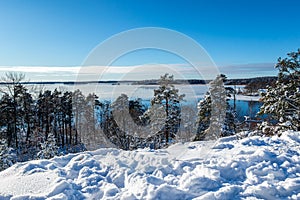 Beautiful calm and tranquil winter landscape mountain view with snowy tree and lake with blue sky horizon.