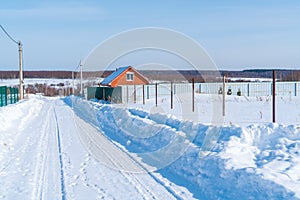 Beautiful calm winter rural landscape with brick house, snow in fields and road