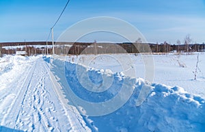 Beautiful calm winter rural landscape with brick house, snow in fields and road