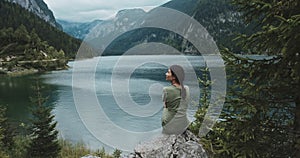 Beautiful calm woman sitting on rock coastline. Girl having moment alone, uniting with nature and enjoying life