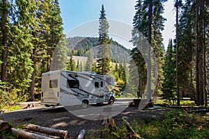 Beautiful campsite in the mountains with an RV and wooden bench photo