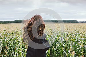 Beautiful carefree long hair asian girl in knitted sweater from behind in the autumn corn field. Sensitivity to nature concept photo