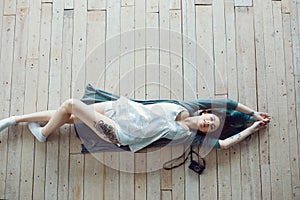 Beautiful carefree young casual woman lying on the wooden floor