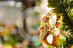 Beautiful carnival mask hanging on the Christmas tree in the background of bright Christmass decorations