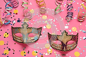 Beautiful carnival masks and party decor on pink background, flat lay